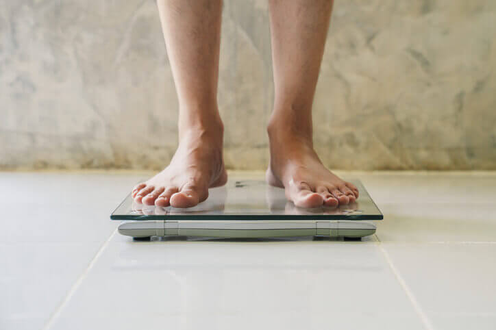 Male on weight scale on floor background